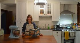 Caroline Smith in her kitchen holding her new book
