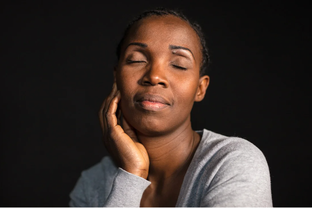 Black woman faces camera, eyes closed, hand resting on cheek.