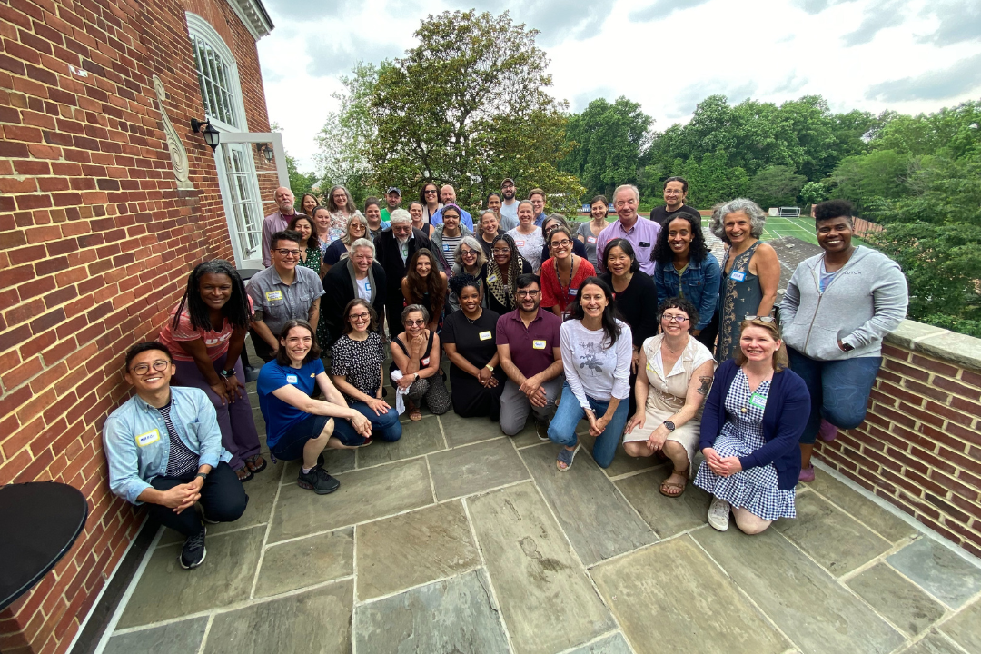 Group of UWP faculty posing on a stone and brick balcony on the Mount Vernon Campus during the June 2024 Faculty Writing Retreat