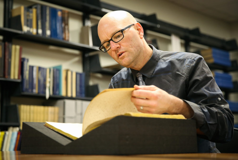 Phillip Troutman is shown poring over a large book at GW's Gelman Library.