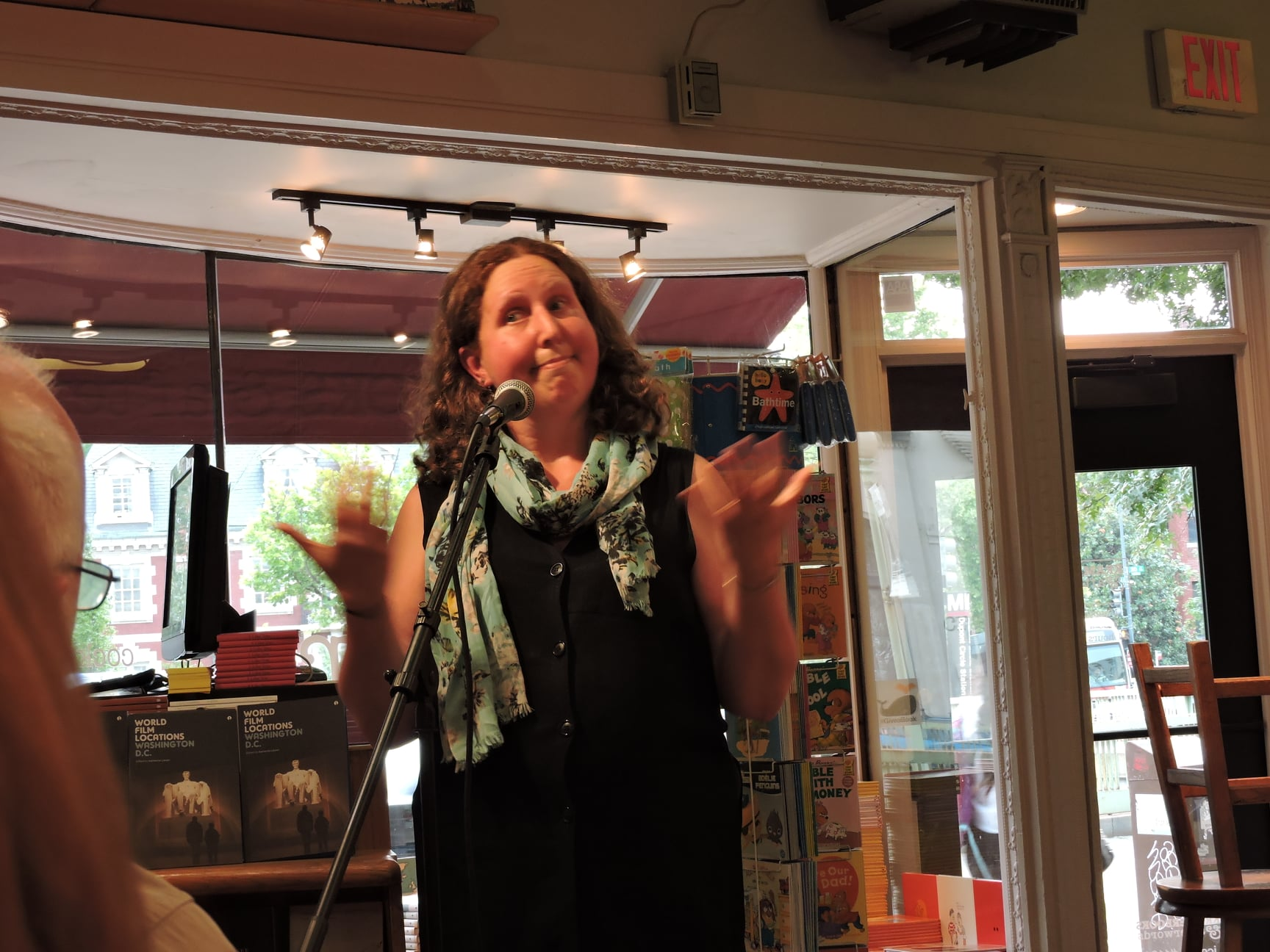 Kathy Larsen at an event for her film locations book launch doing jazz hands on stage