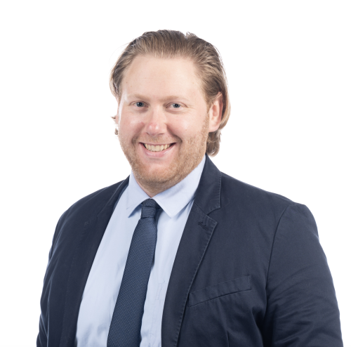 Headshot of Jacob Richter against a white background. He is wearing a black suit with a light blue shirt and dark blue tie.