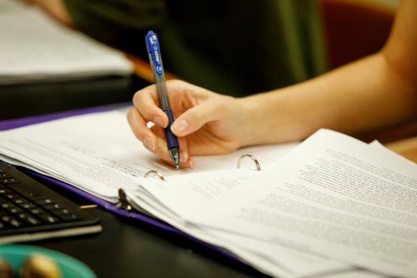 A person's hand holding a pen over a notebook