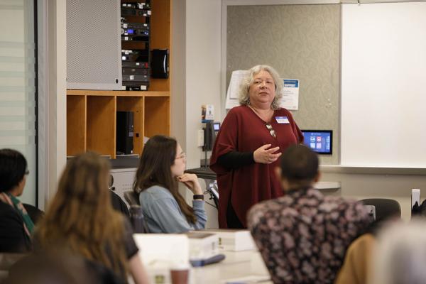 Randi Kristensen standing in front of a room of students and teachers presenting