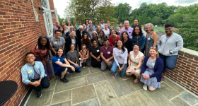 Group of UWP faculty posing on a stone and brick balcony on the Mount Vernon Campus during the June 2024 Faculty Writing Retreat