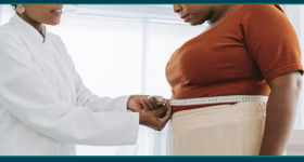 Black femaile Doctor measures black female patient's waist. 
